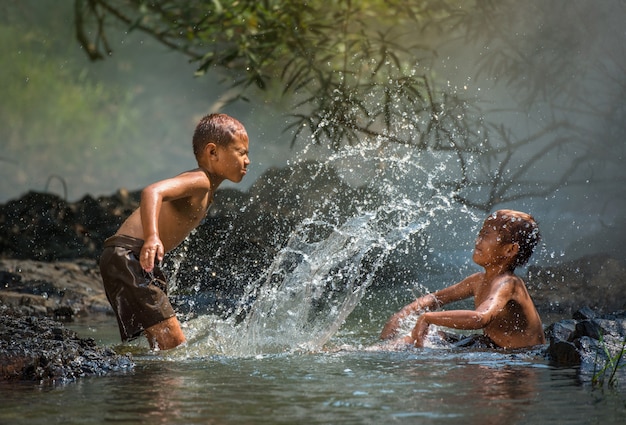 Das glückliche lustige spielende Wasser des Freunds im Wasserstrom in der Landschaft