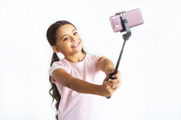 Das glückliche Mädchen, das Selfie auf dem weißen Wandhintergrund macht