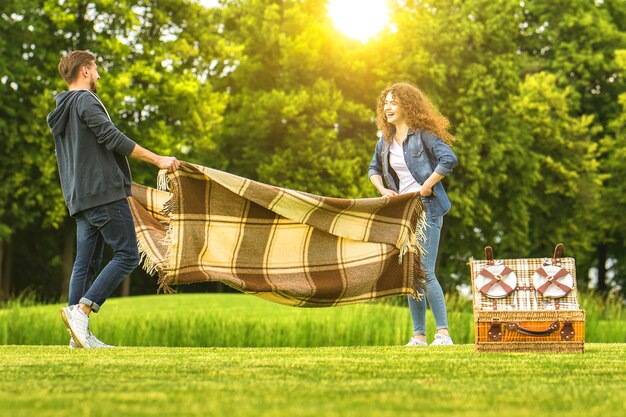 Das glückliche Paar hält eine Decke im grünen Park