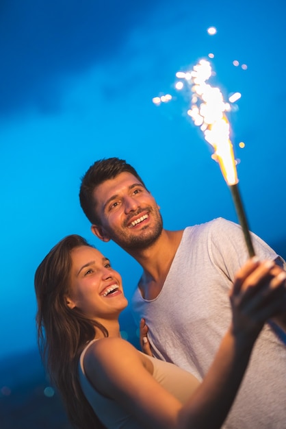 Das glückliche Paar hält einen Feuerwerksstock. abend nacht zeit