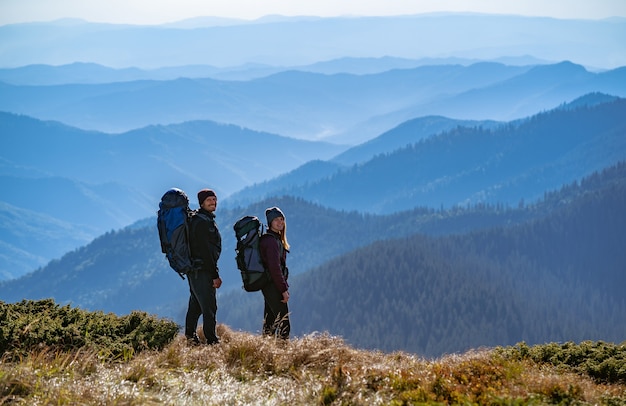 Das glückliche Paar mit Rucksäcken steht auf dem Berg mit schöner Aussicht