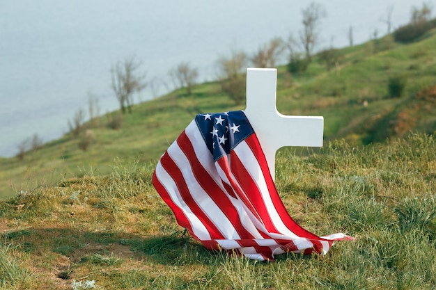 Das Grab eines Soldaten. Amerikanische Flagge über dem Grab des verstorbenen Soldaten. Am Grab eine Militärmütze