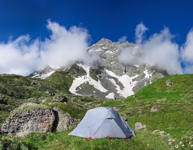 Das graue Zelt im hohen Gras auf einem Hintergrund von Bergen und Felsen. Georgia.