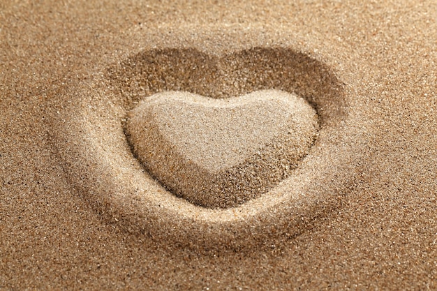 Das Herzsymbol ist auf sauberem Sand gezeichnet