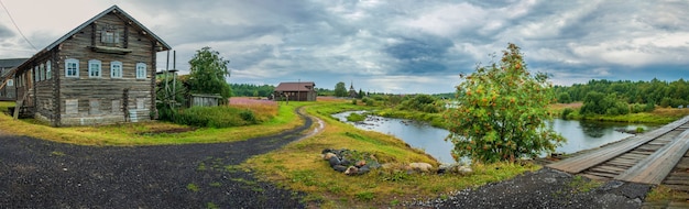 Das historische Dorf Pyalma in Karelien Russland mit alten Holzhäusern, einer Brücke über den Fluss und einer Kirche im Sommer.