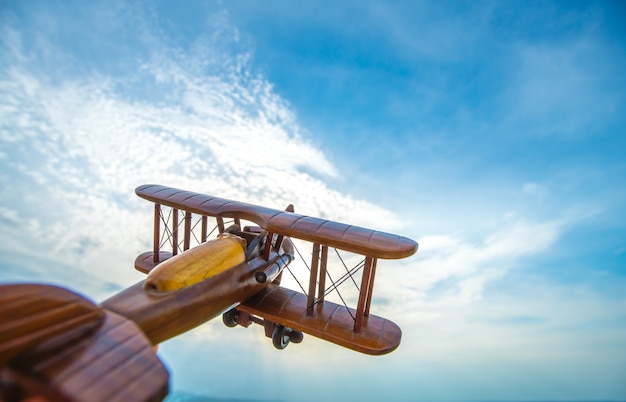 Das Holzflugzeug auf dem Hintergrund des blauen Himmels