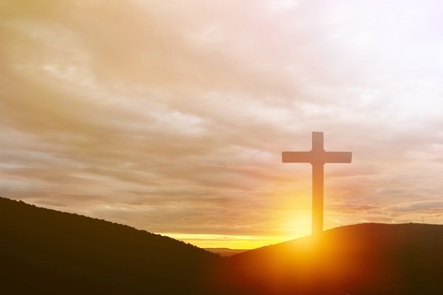 Das Holzkreuz auf dem Berg auf dem Hintergrund des Sonnenuntergangs