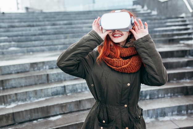 Das junge Hipster-Mädchen spielt die mobile Spiel-App für virtuelle Realität auf einem Smartphone, das an einer modernen VR-Brille befestigt ist