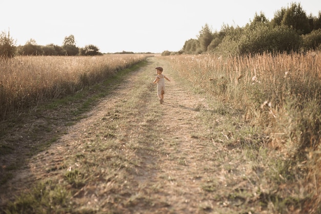 Das Junge macht Spaß und läuft aktiv auf dem Feld ein aufrichtiger und fröhlicher Junge Kindheit auf dem Land