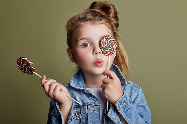 Das junge Mädchen, das runde Süßigkeit isst, leckt Lutscher