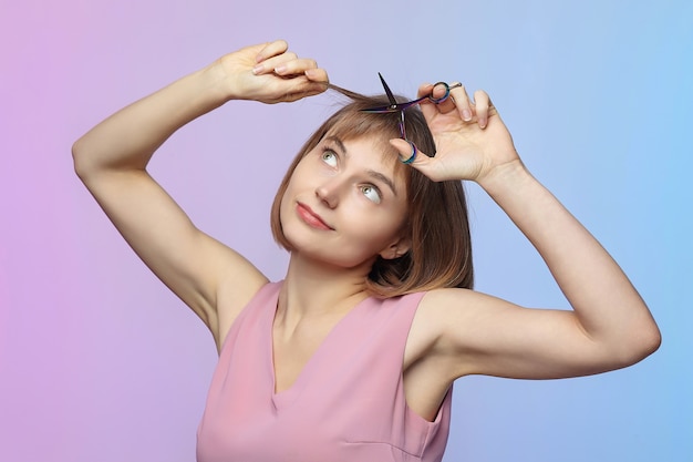 Das junge Mädchen hält eine Schere in der Hand und steht kurz vor einem Haarschnitt