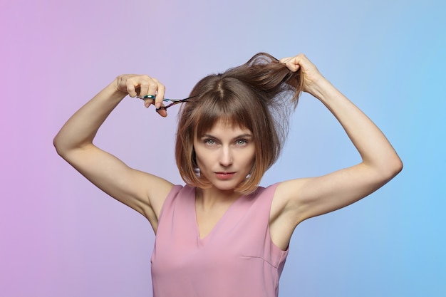 Das junge Mädchen hält eine Schere in der Hand und steht kurz vor einem Haarschnitt