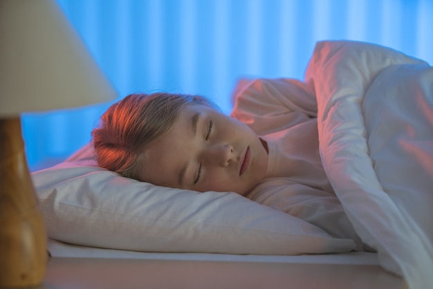 Das junge Mädchen schläft auf dem Bett. Abend Nachtzeit