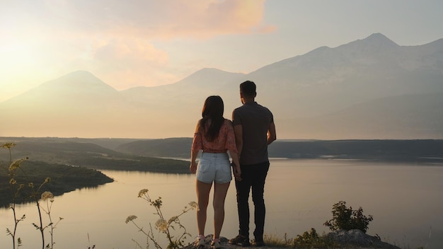 Das junge Paar steht auf dem Berggipfel auf dem schönen Flusshintergrund