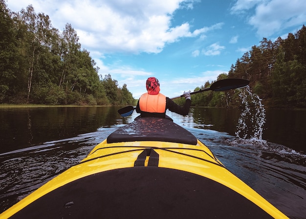 Das Kajak schwimmt auf dem Zügelmädchen mit einem Paddel