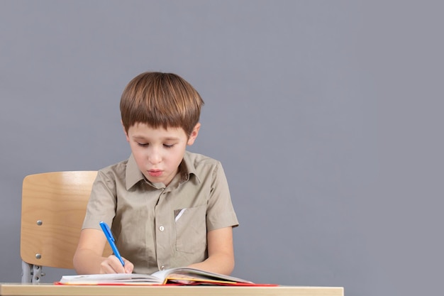 Das Kind am Tisch macht Hausaufgaben Grundschüler mit einem Lehrbuch