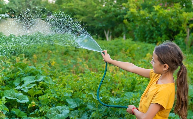 Das Kind bewässert den Garten mit einem Schlauch Selektiver Fokus