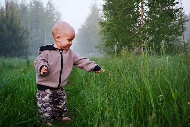 Das Kind geht auf dem Gras im Wald spazieren.