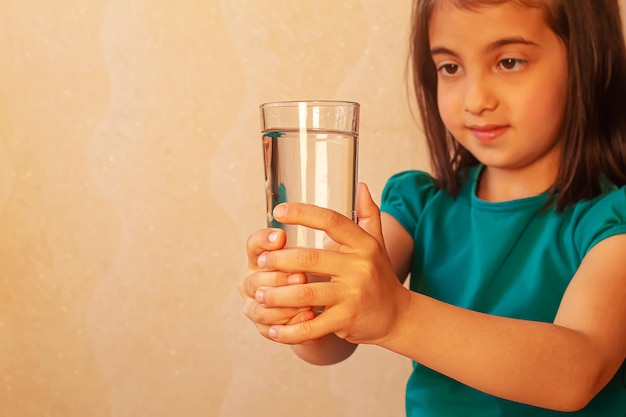 Das Kind hält ein Glas Wasser in ihren Händen selektive Fokusnatur