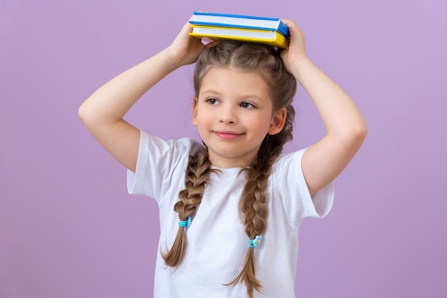 Das Kind hält ein paar Bücher und schaut nachdenklich in die Ferne.