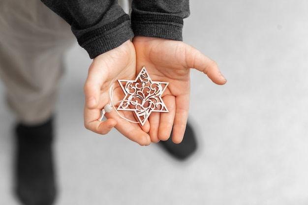 Das Kind hält in seinen Händen eine dekorative Schneeflocke einen Stern Dekoration für den Weihnachtsbaum