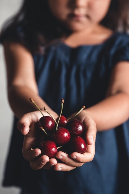 Foto das kind hält leckere kirschen in den händen