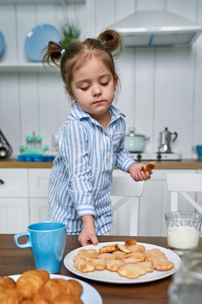 Das Kind in der Küche will Kekse mit Tee essen