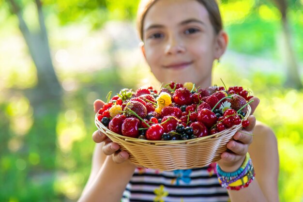 Das Kind isst Beeren im Garten Selektiver Fokus