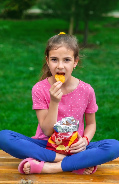 Das Kind isst Chips im Park Selektiver Fokus