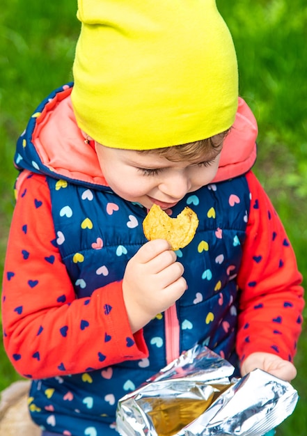 Das Kind isst Chips im Park Selektiver Fokus