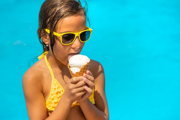 Das Kind isst Eis in der Nähe des Pools. Selektiver Fokus. Kind.