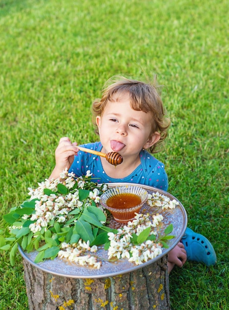 Das Kind isst Honig im Garten. Selektiver Fokus