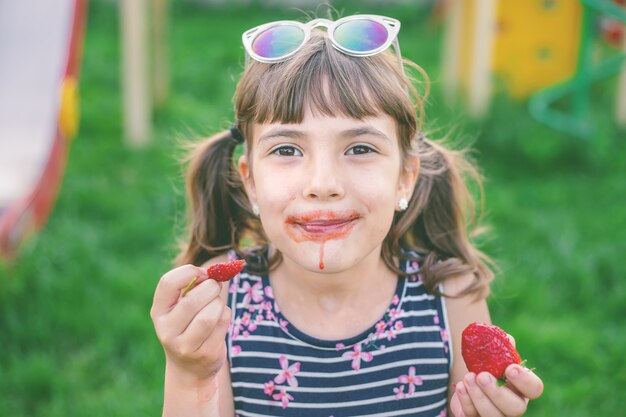 Das Kind isst im Sommer Erdbeeren