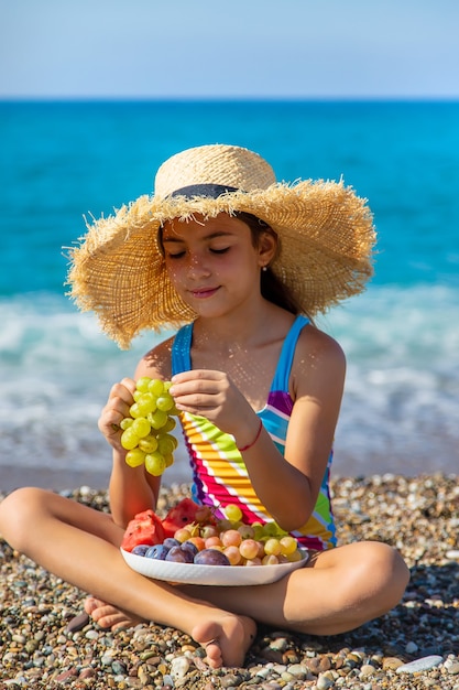 Das Kind isst Obst am Meer. Selektiver Fokus.