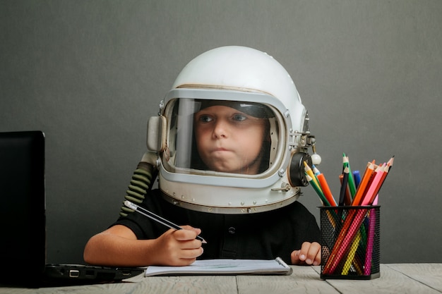 Das Kind lernt in der Schule aus der Ferne und trägt einen Astronautenhelm. zurück zur Schule