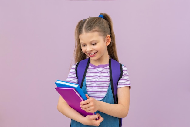 Das Kind liest ein interessantes Buch. Ein Schulmädchen mit einem Buch auf einem isolierten Hintergrund.