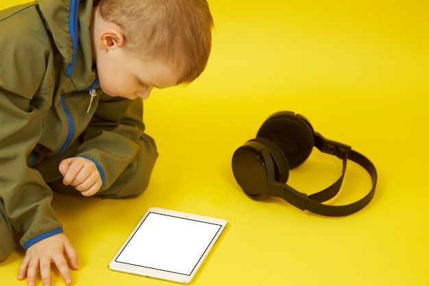 Das Kind nutzt ein Tablet und Kopfhörer für Online-Spiele, kommuniziert mit Freunden und lernt online. Das Konzept der modernen Entwicklung von Kindern.