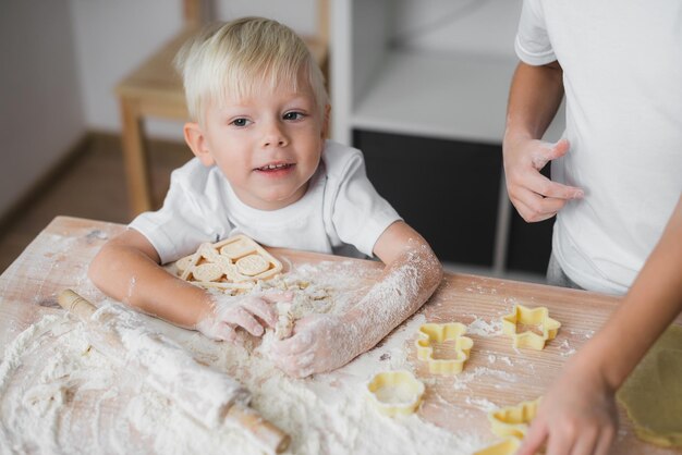 Das Kind sitzt am Tisch und hilft seinem Bruder mit hausgemachtem Kuchen, er ist glücklich und lächelt.