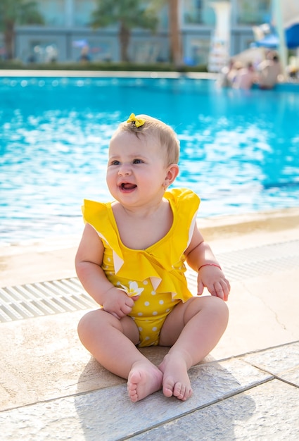 Das Kind sitzt im Badeanzug am Pool.