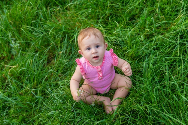 Das Kind sitzt im Sommer auf dem Gras. Selektiver Fokus. Natur.