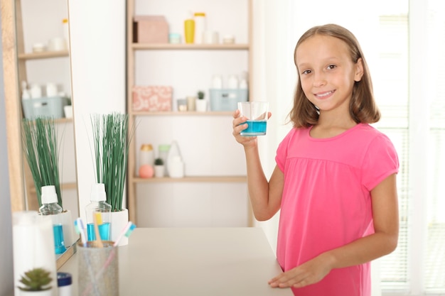 Das Kind spült den Mund mit einem Mundwasser aus Mundgesundheit bei Kindern