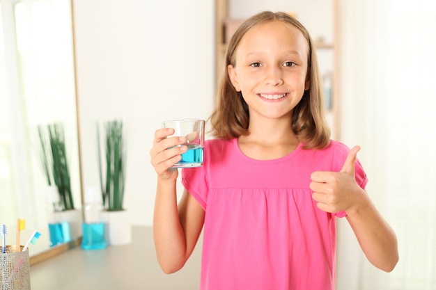 Das Kind spült den Mund mit einem Mundwasser aus Mundgesundheit bei Kindern