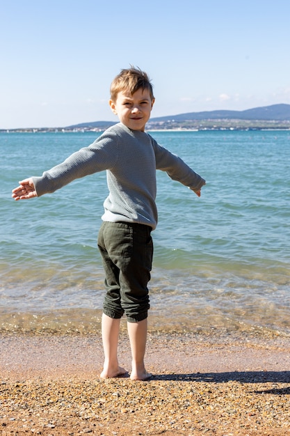 Das Kind steht am Meer freudig ausgestreckte Arme Blick von hinten
