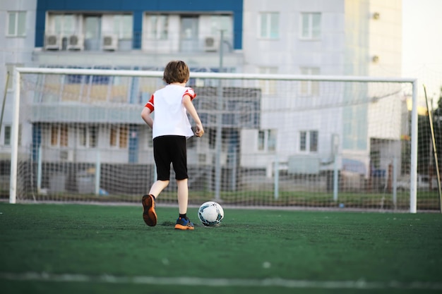 Das Kind treibt Sport im Stadion Der Junge trainiert, bevor er Fußball spielt