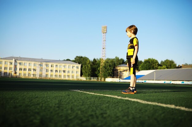 Das Kind treibt Sport im Stadion Der Junge trainiert, bevor er Fußball spielt