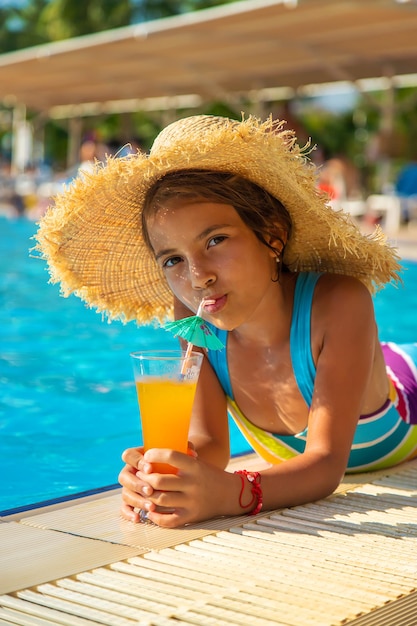 Das Kind trinkt einen Cocktail am Pool. Selektiver Fokus.