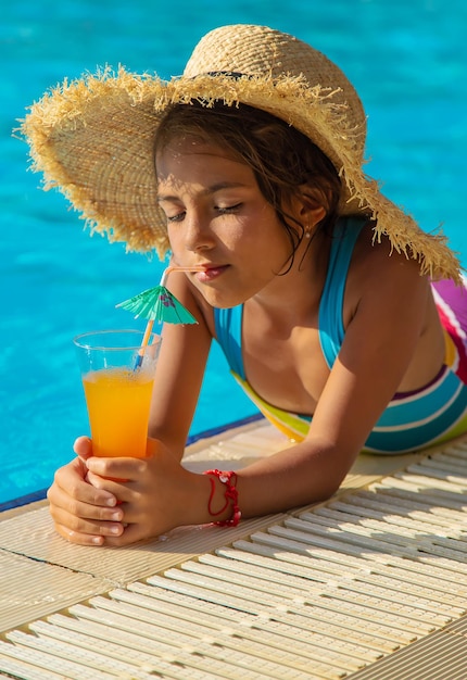 Das Kind trinkt einen Cocktail am Pool. Selektiver Fokus.