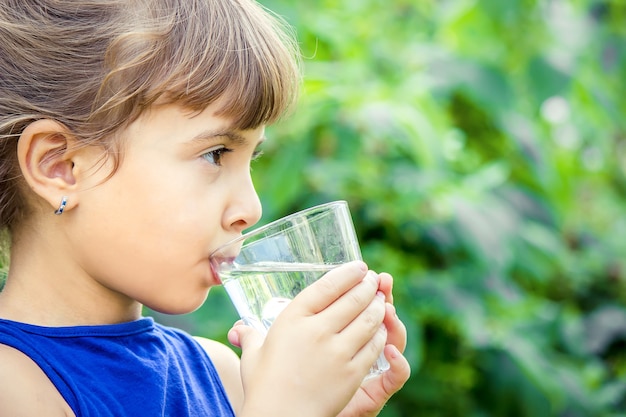 Das Kind trinkt im Sommer sauberes Wasser. Selektiver Fokus.