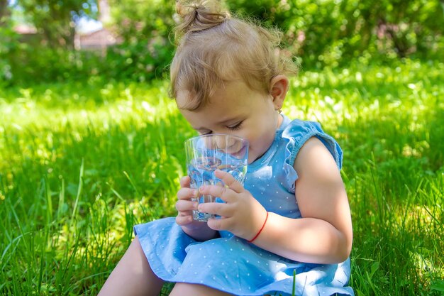 Das Kind trinkt Wasser aus einem Glas Selektiver Fokus