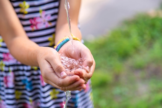 Das Kind tropft Wasser in seine Hände Selektiver Fokus